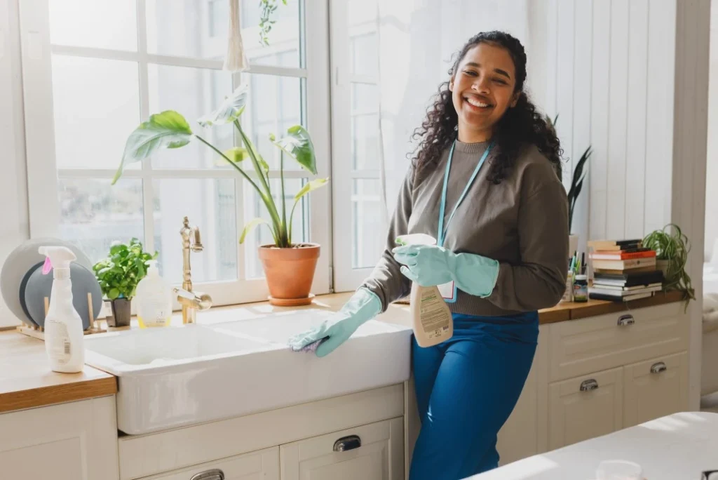 A woman smiling whole wiping the sink