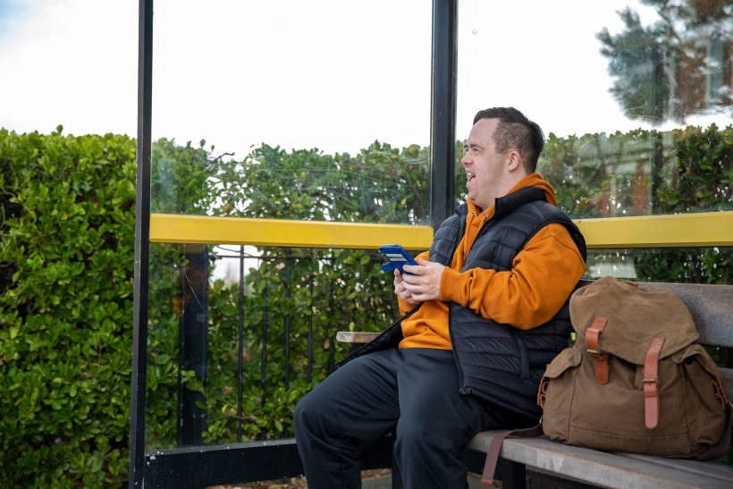 A disabled man sitting on a bench while smiling